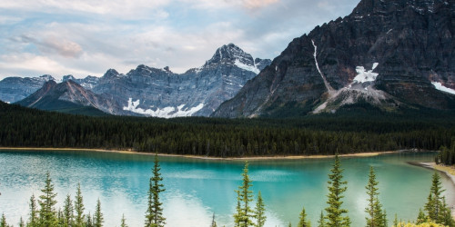 Lake in Canada with green trees and black mountains&nbsp;